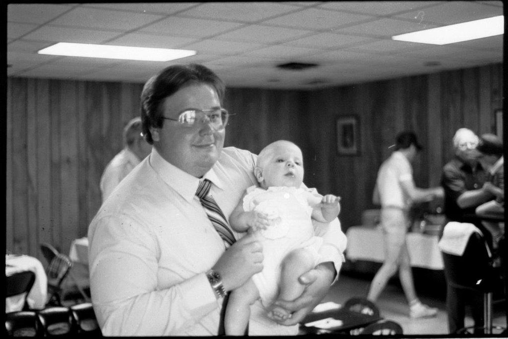 man in a white shirt is holding a baby