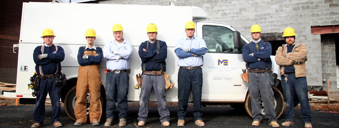 a group of men posing in front of white Massey Electric van