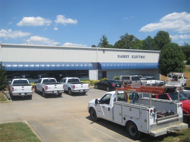 Massey Electric blue and white building with trucks parked in front of it