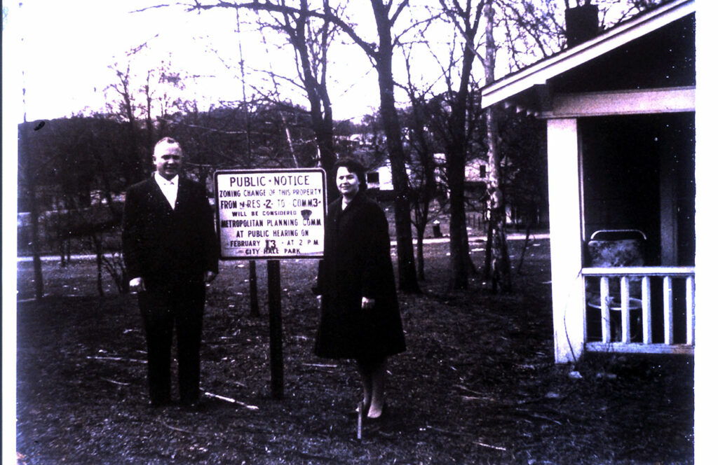 man and woman posing in front of the notice sign